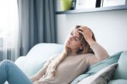 PCO-Syndrom: Eine Frau sitzt nachdenklich auf einem Sofa PCO-Syndrom: Eine Frau sitzt nachdenklich auf einem Sofa
